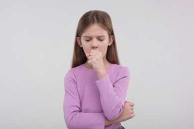 Photo of Sick girl coughing on light background. Cold symptoms