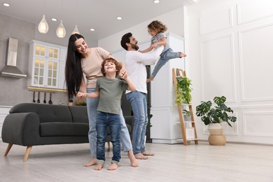 Happy family dancing and having fun at home, low angle view