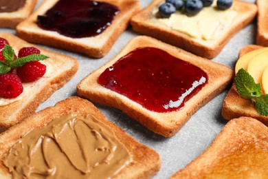 Photo of Tasty toasts with different spreads and fruits on light grey table, closeup