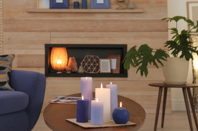 Photo of Burning candles on table in living room