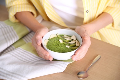 Photo of Young woman with bowl of healthy smoothie at table, closeup