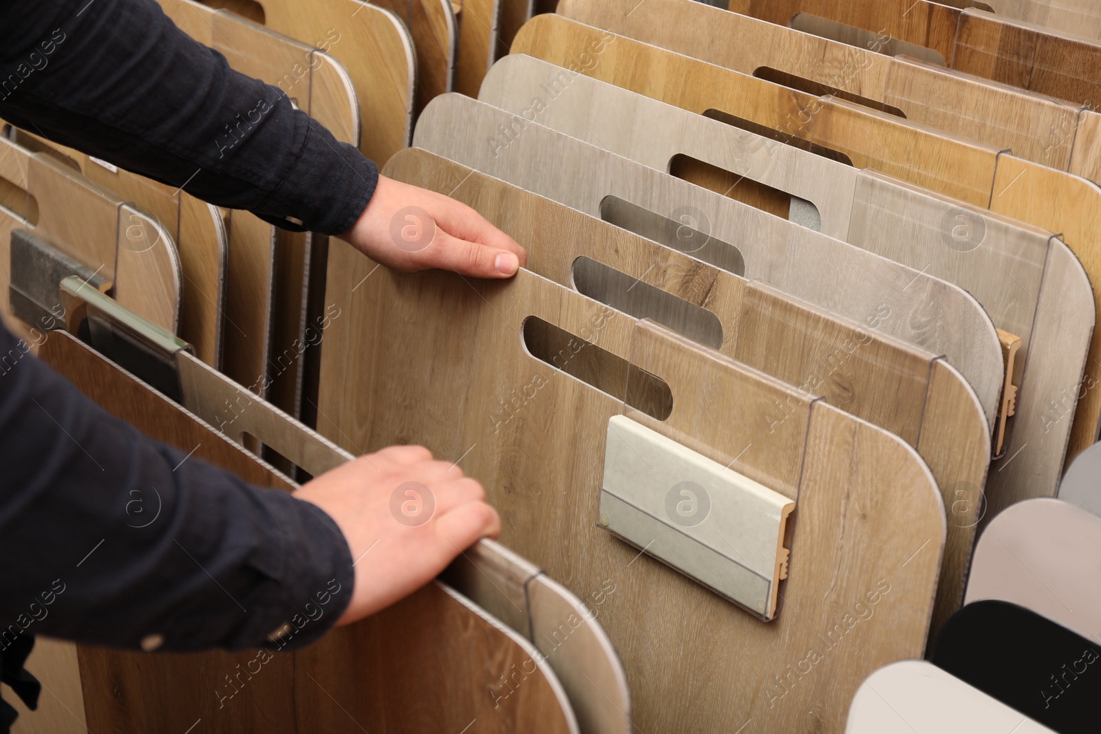 Photo of Man choosing wooden flooring among different samples in shop, closeup