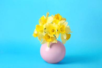 Photo of Bouquet of beautiful yellow daffodils in vase on light blue background