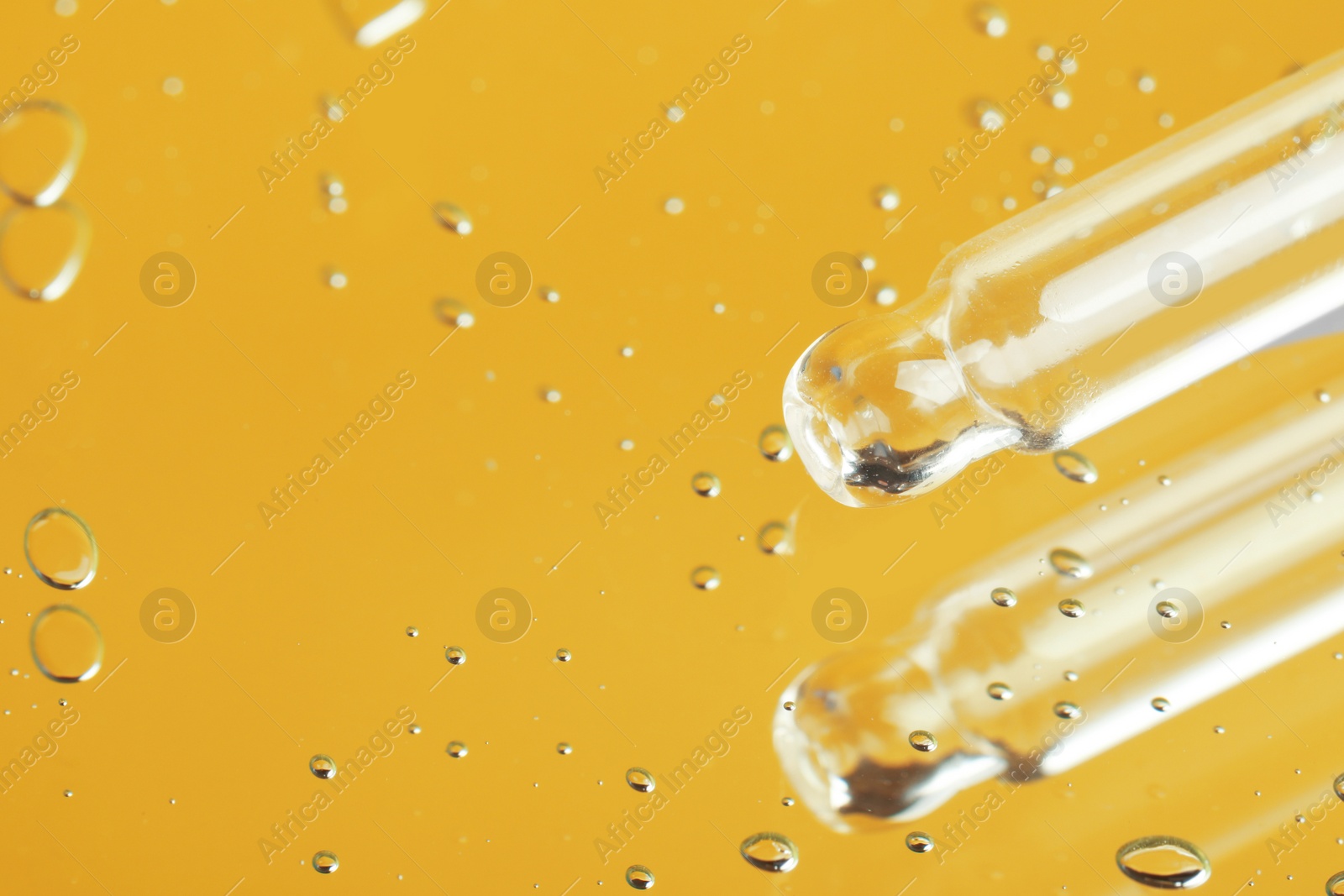 Photo of Pipette near serum drops on beautiful mirror, closeup with space for text. Toned in yellow