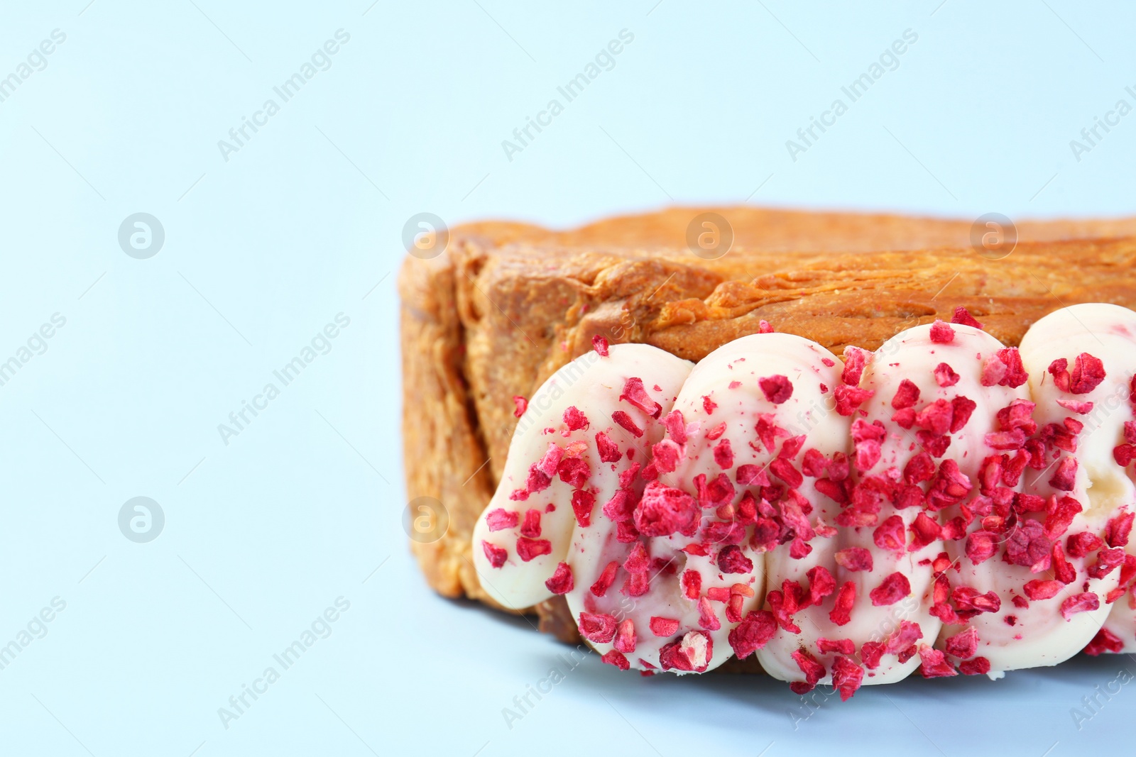 Photo of One supreme croissant with cream on light blue background, closeup with space for text. Tasty puff pastry