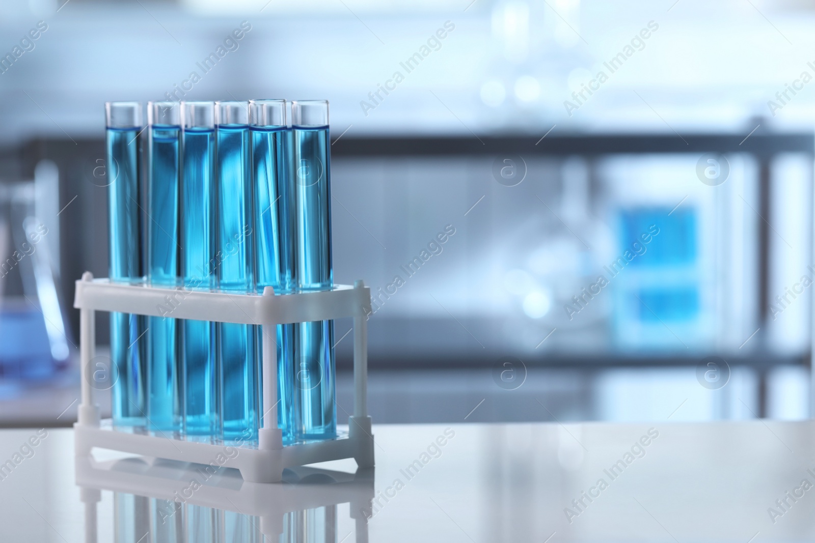 Photo of Test tubes with light blue liquid on table in laboratory. Space for text