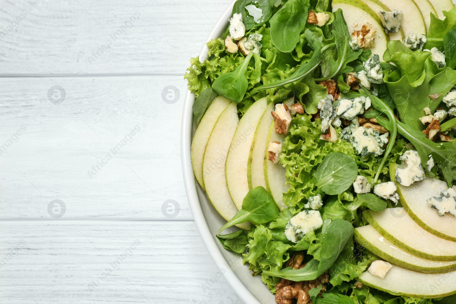 Photo of Fresh salad with pear on white wooden table, top view. Space for text