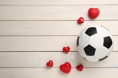 Soccer ball and hearts on white wooden background, flat lay. Space for text