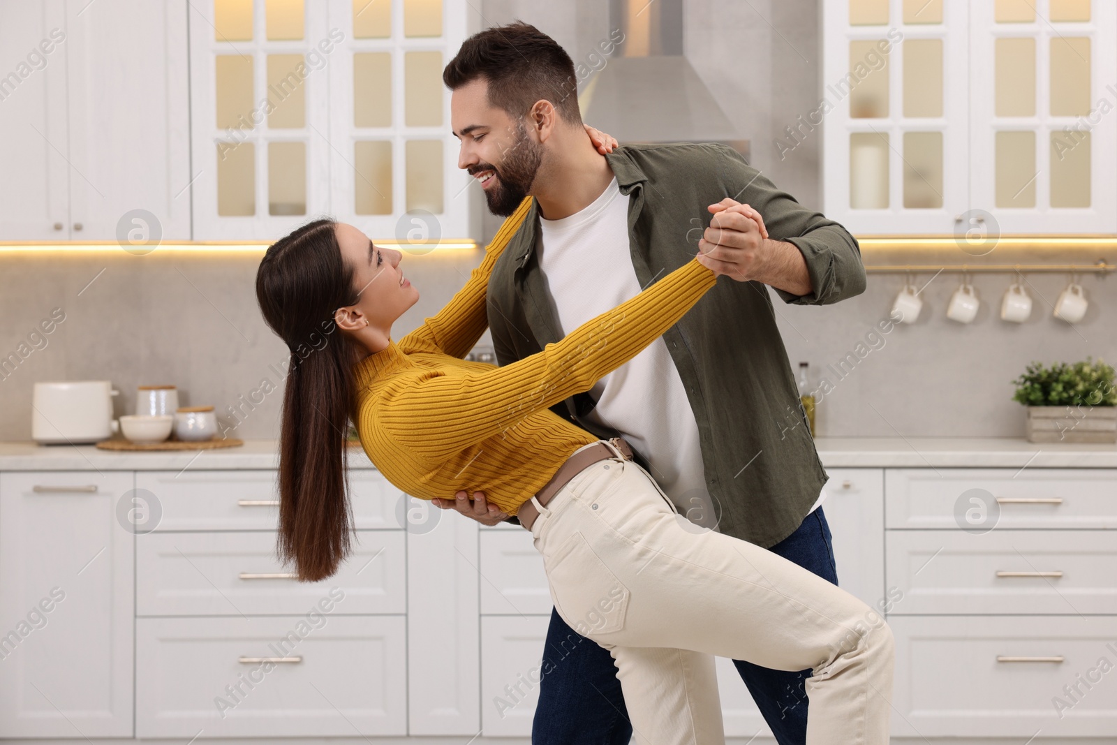 Photo of Happy lovely couple dancing together in kitchen