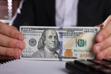 Money exchange. Man holding dollar banknotes at table, closeup