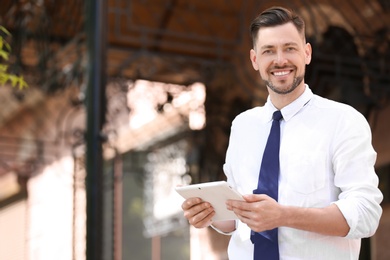 Portrait of young businessman with tablet outdoors