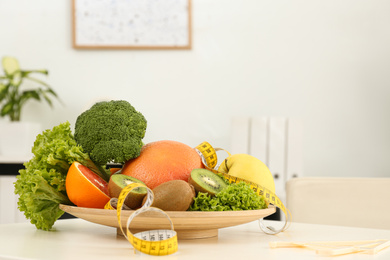 Photo of Nutritionist's workplace with fruits, vegetables, measuring tape and body fat caliper on table