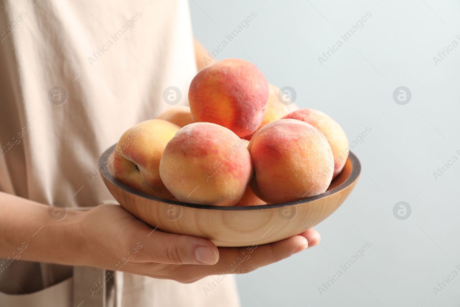 Photo of Woman holding plate with fresh sweet peaches, closeup