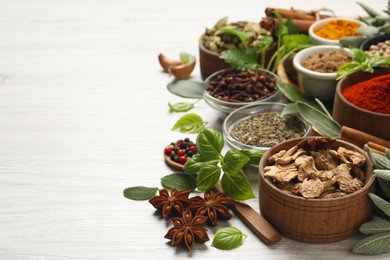 Photo of Different fresh herbs and spices on white wooden table, closeup. Space for text