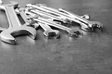 Photo of New wrenches on grey background, closeup with space for text. Plumber tools