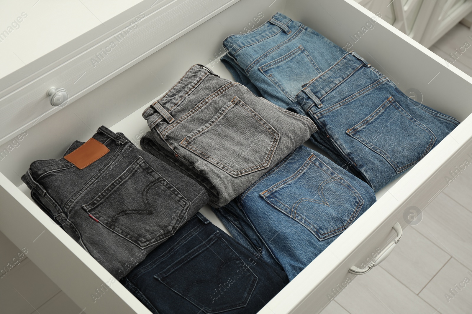 Photo of Folded clothes in open drawer. Apparel storage