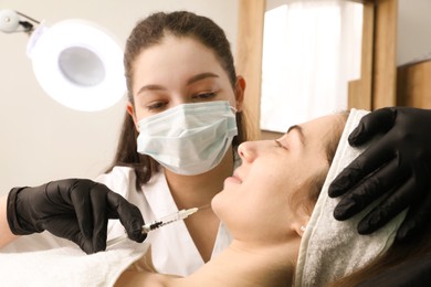 Photo of Cosmetologist giving facial injection to patient in clinic. Cosmetic surgery