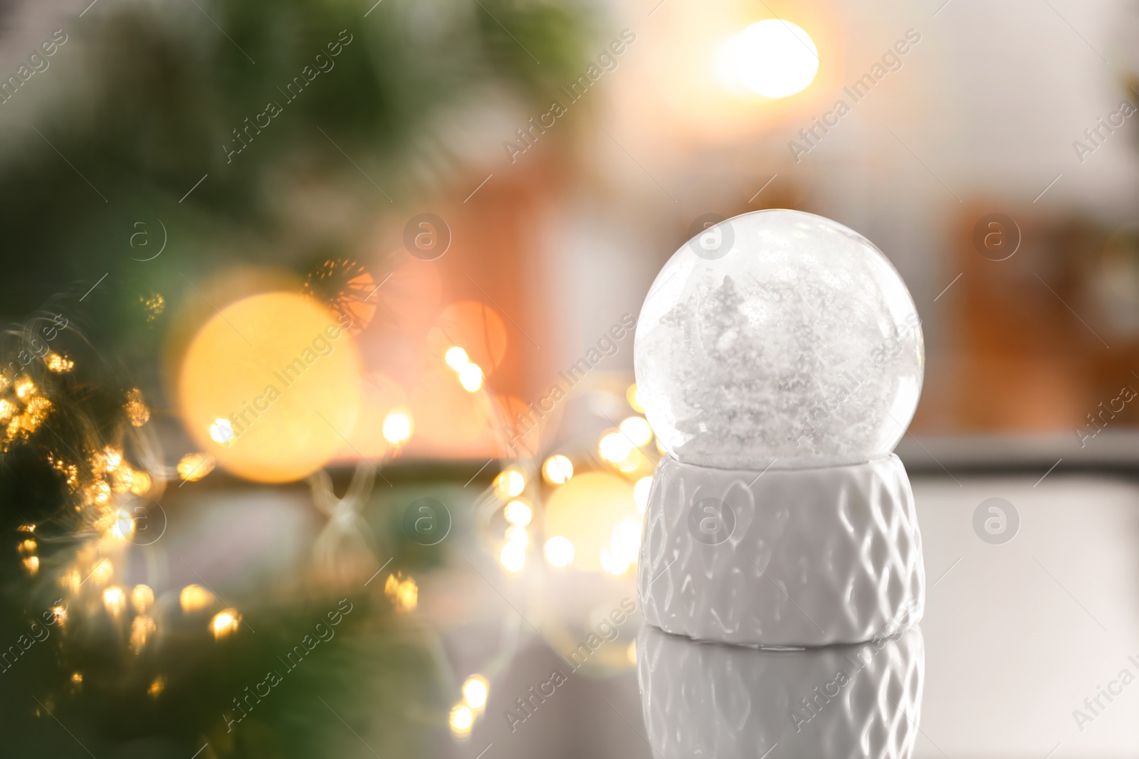 Photo of Decorative Christmas snow globe on mirror surface