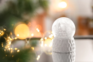 Photo of Decorative Christmas snow globe on mirror surface