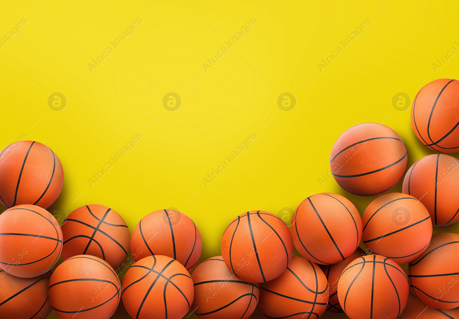 Image of Many orange basketball balls on yellow background. Space for text