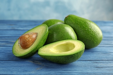 Tasty ripe green avocados on wooden table