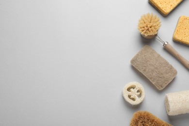 Photo of Sponges, brush and loofah on light grey background, flat lay. Space for text