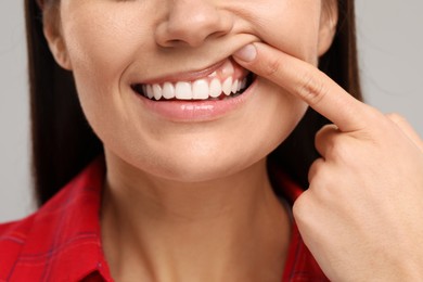 Photo of Woman showing her clean teeth on light grey background, closeup