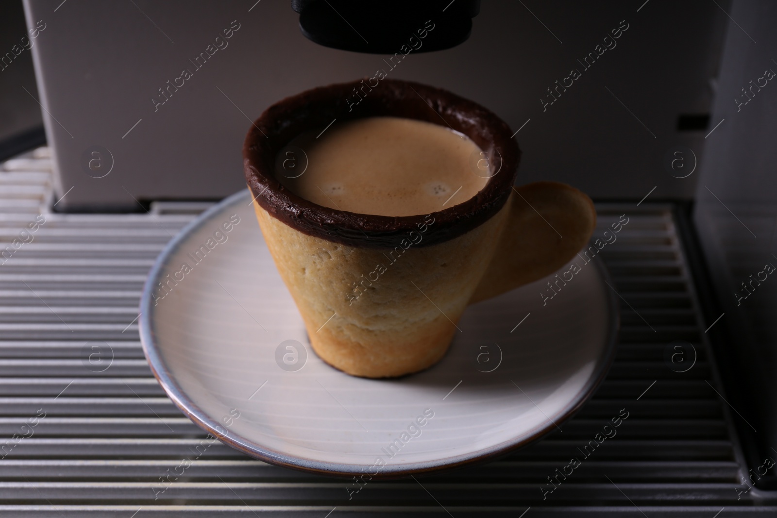 Photo of Coffee machine with delicious edible biscuit cup