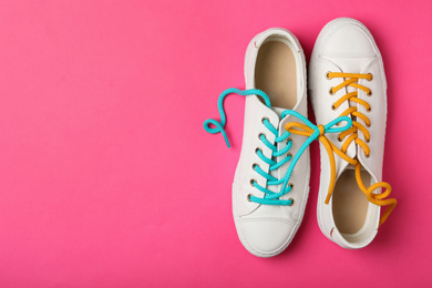 Photo of Shoes tied together on pink background, flat lay with space for text. April Fool's Day
