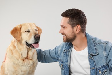 Man hugging with adorable Labrador Retriever dog on light gray background. Lovely pet