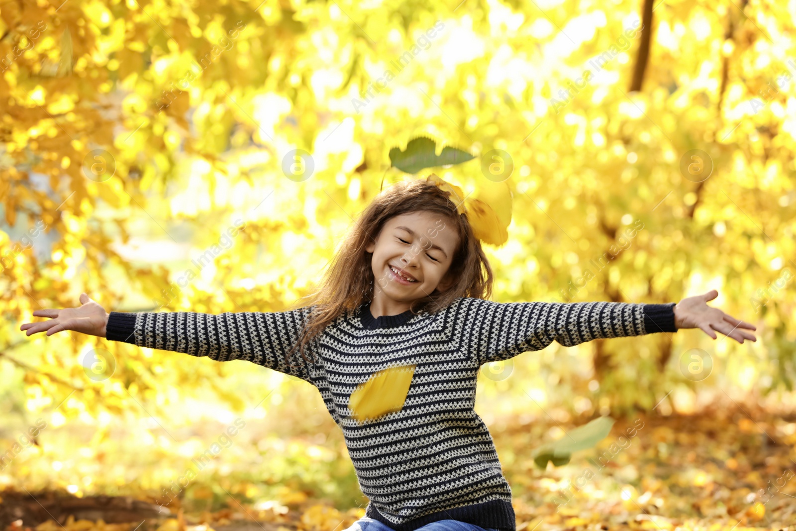 Photo of Cute little girl having fun in park. Autumn walk