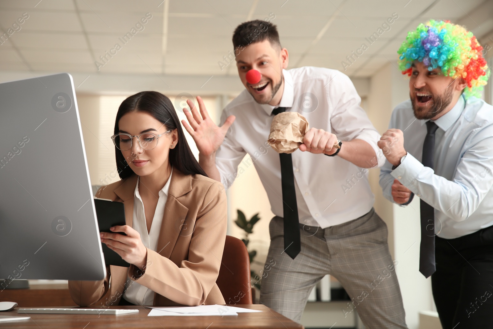 Photo of Men popping paper bag behind their colleague in office. Funny joke