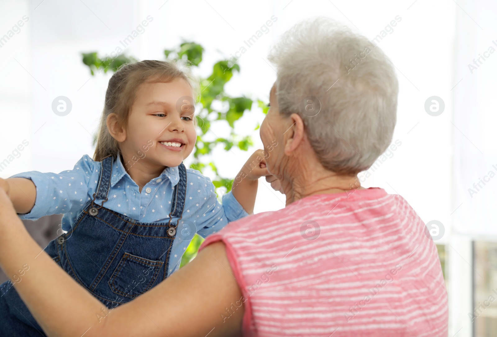 Photo of Cute girl and her grandmother playing together at home