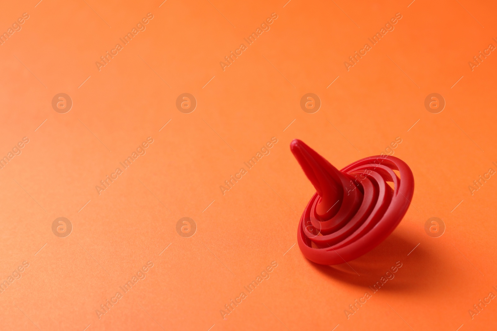 Photo of One red spinning top on orange background, space for text