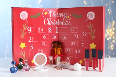 Photo of Christmas advent calendar with perfumes, skin care and decorative cosmetics on table