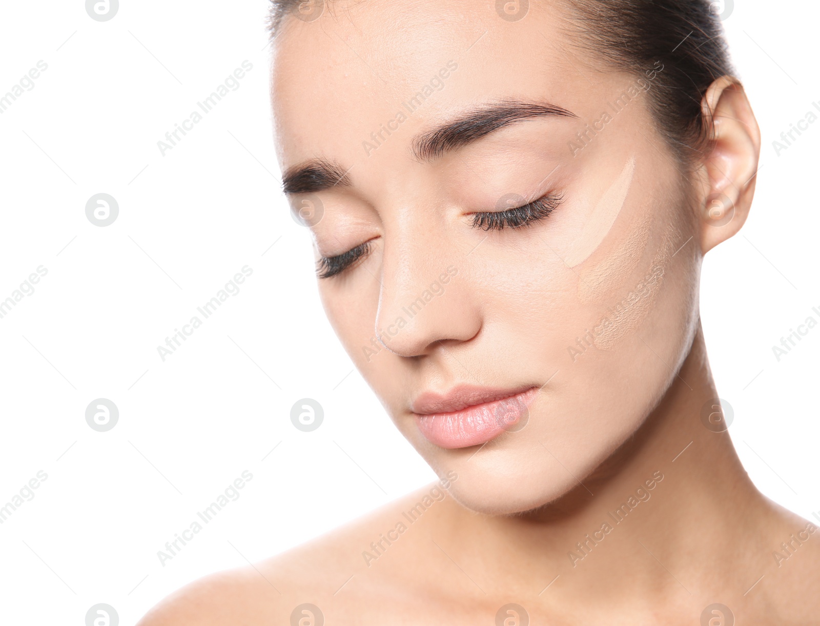 Photo of Young woman with different shades of skin foundation on her face against white background