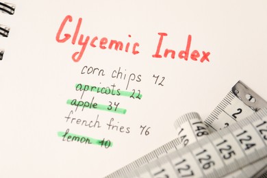 Photo of Glycemic Index. Notebook with information and measuring tape, closeup