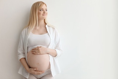 Portrait of beautiful pregnant woman on light background. Space for text