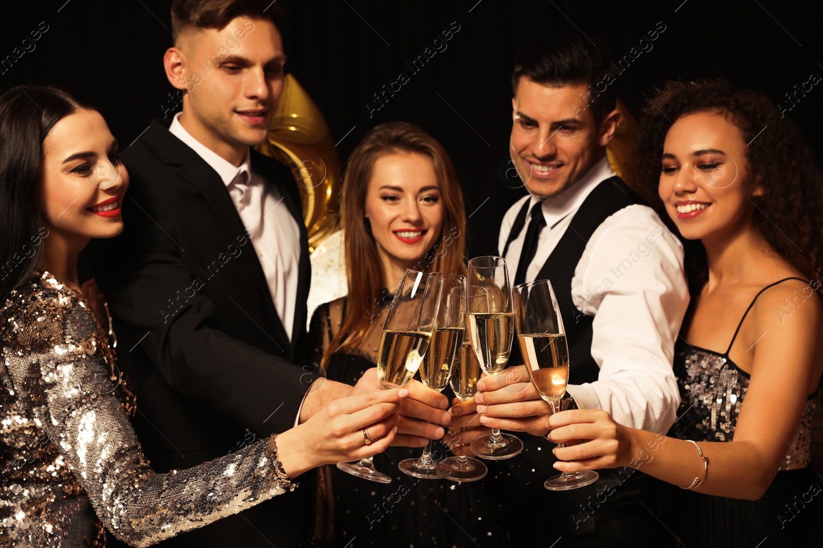 Photo of Happy friends with glasses of sparkling wine celebrating New Year on black background