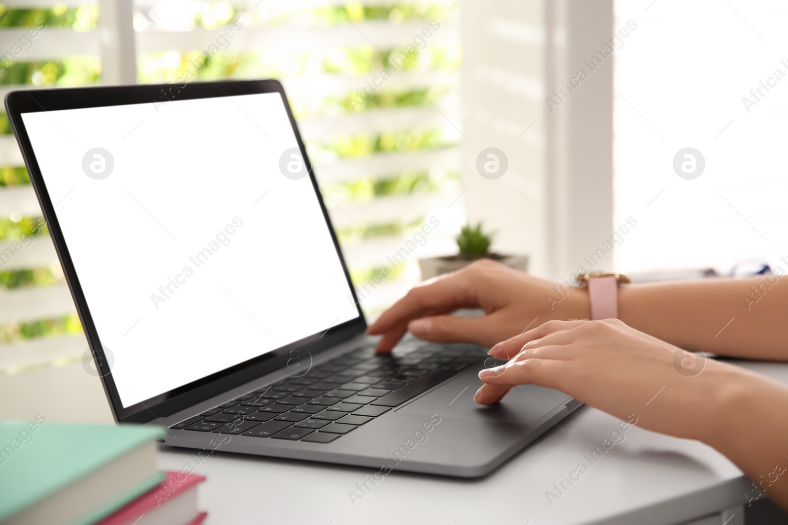 Photo of Woman working with modern laptop at white table, closeup