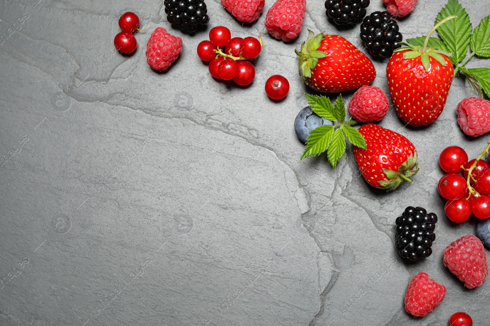 Photo of Different fresh berries on grey background, flat lay. Space for text