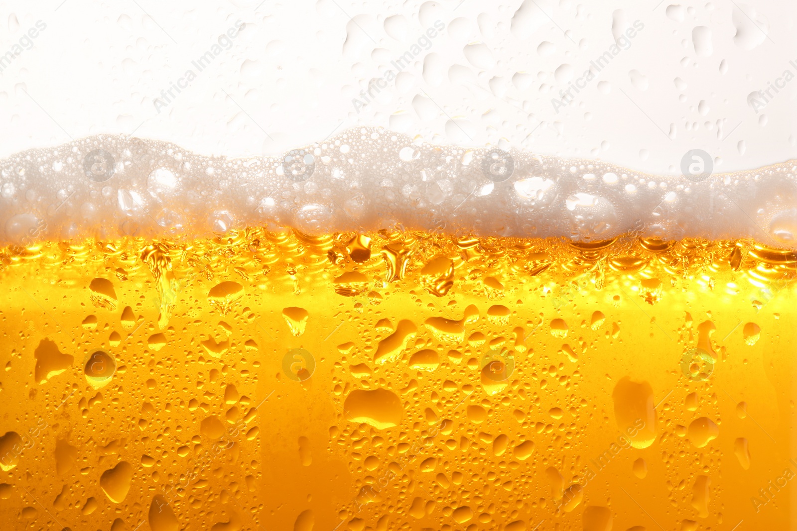 Photo of Glass of tasty cold beer with foam and condensation drops on white background, closeup