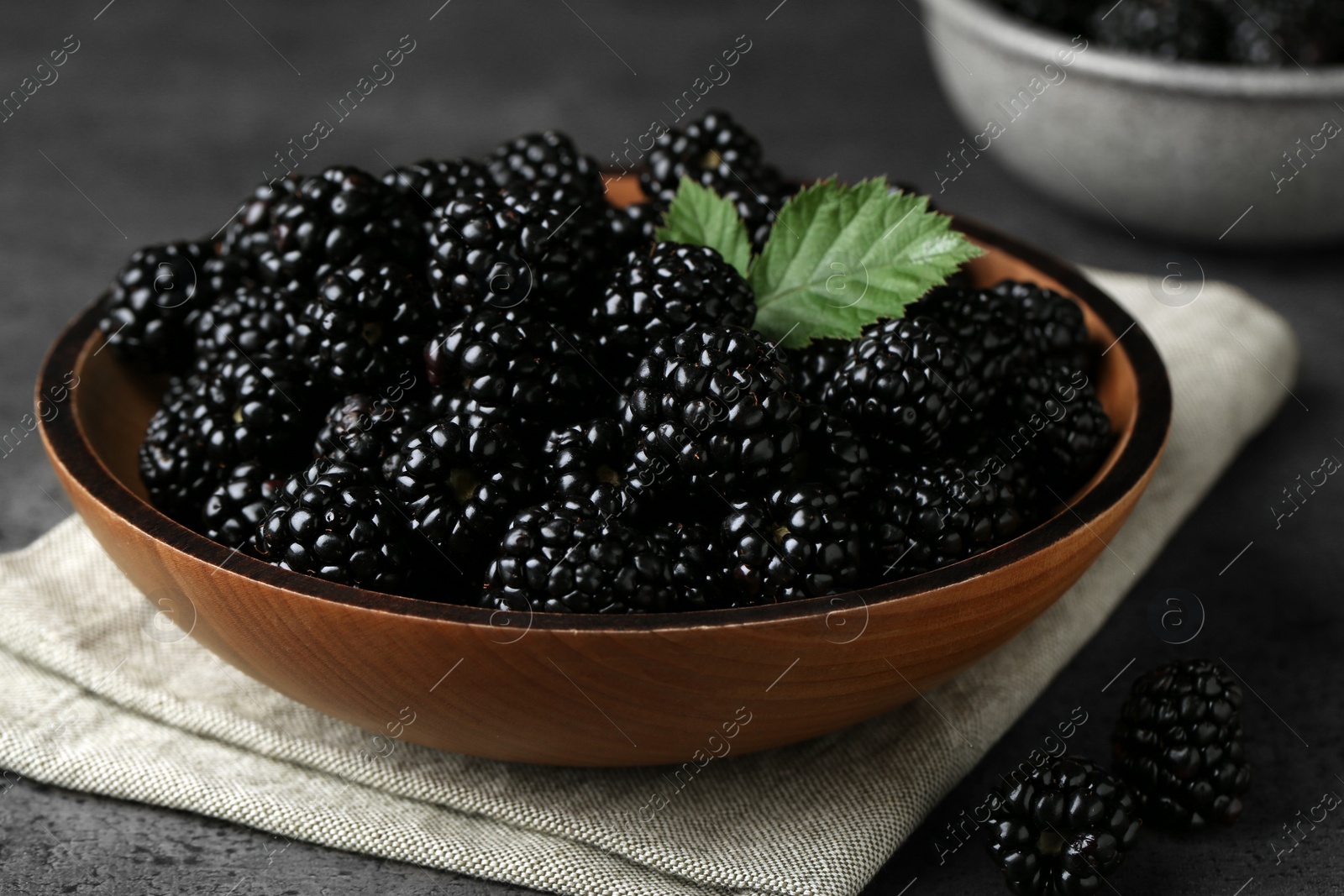 Photo of Bowl with fresh ripe blackberries on dark grey table, closeup