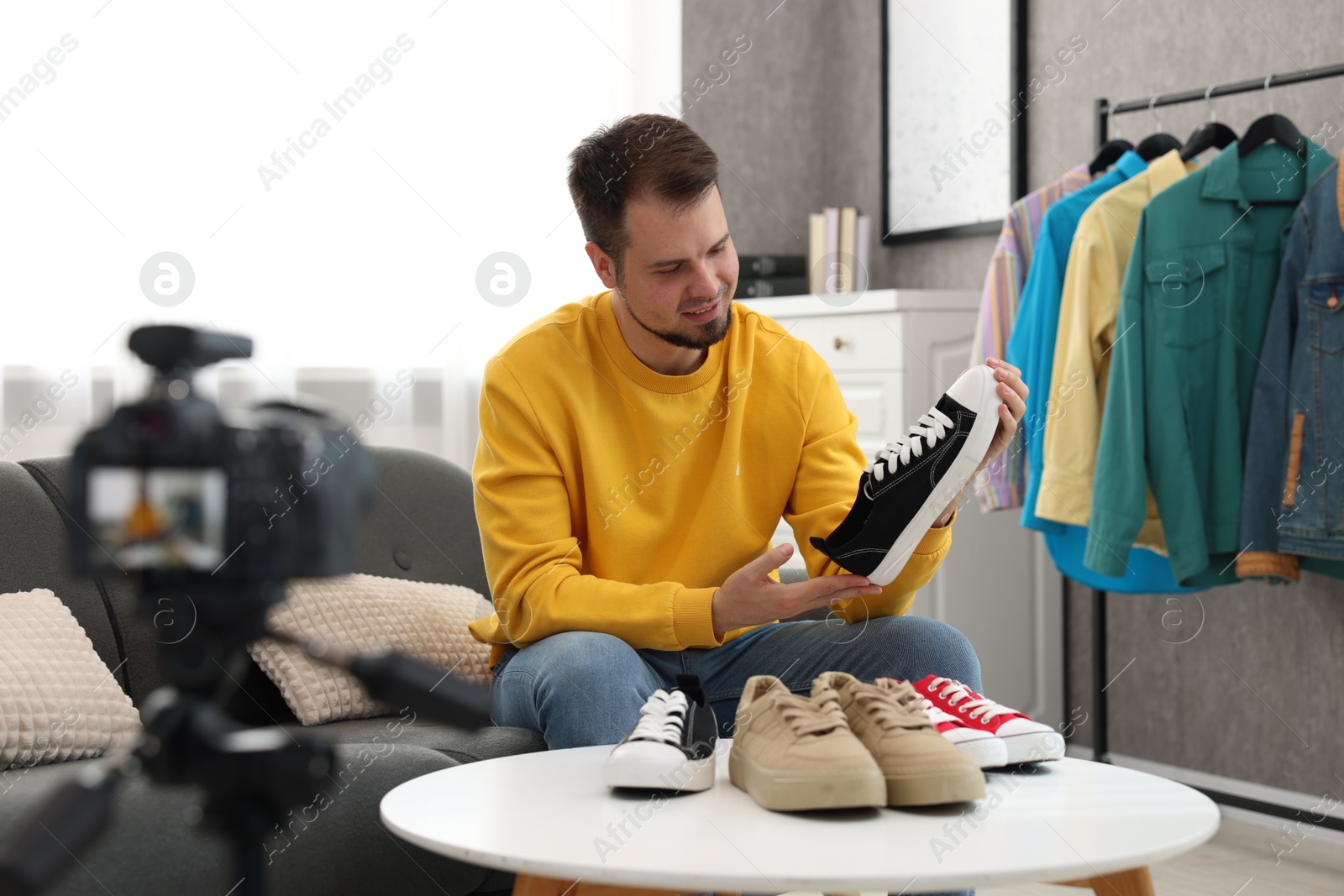 Photo of Smiling fashion blogger looking at shoe while recording video at home