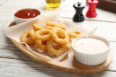 Photo of Plate with fried onion rings and sauces on table