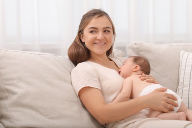 Photo of Mother holding her cute newborn baby on sofa indoors, space for text