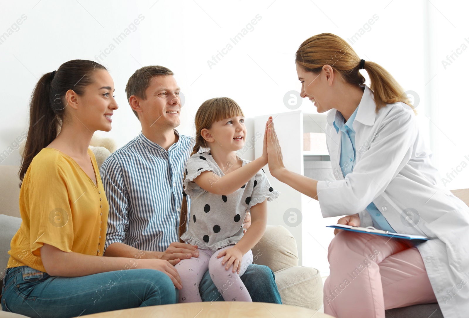 Photo of Children's doctor visiting little girl with parents at home. House call