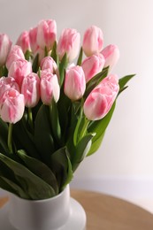 Beautiful bouquet of fresh pink tulips on table against light background, closeup