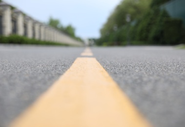 Photo of Yellow dividing lines on asphalt road, closeup view