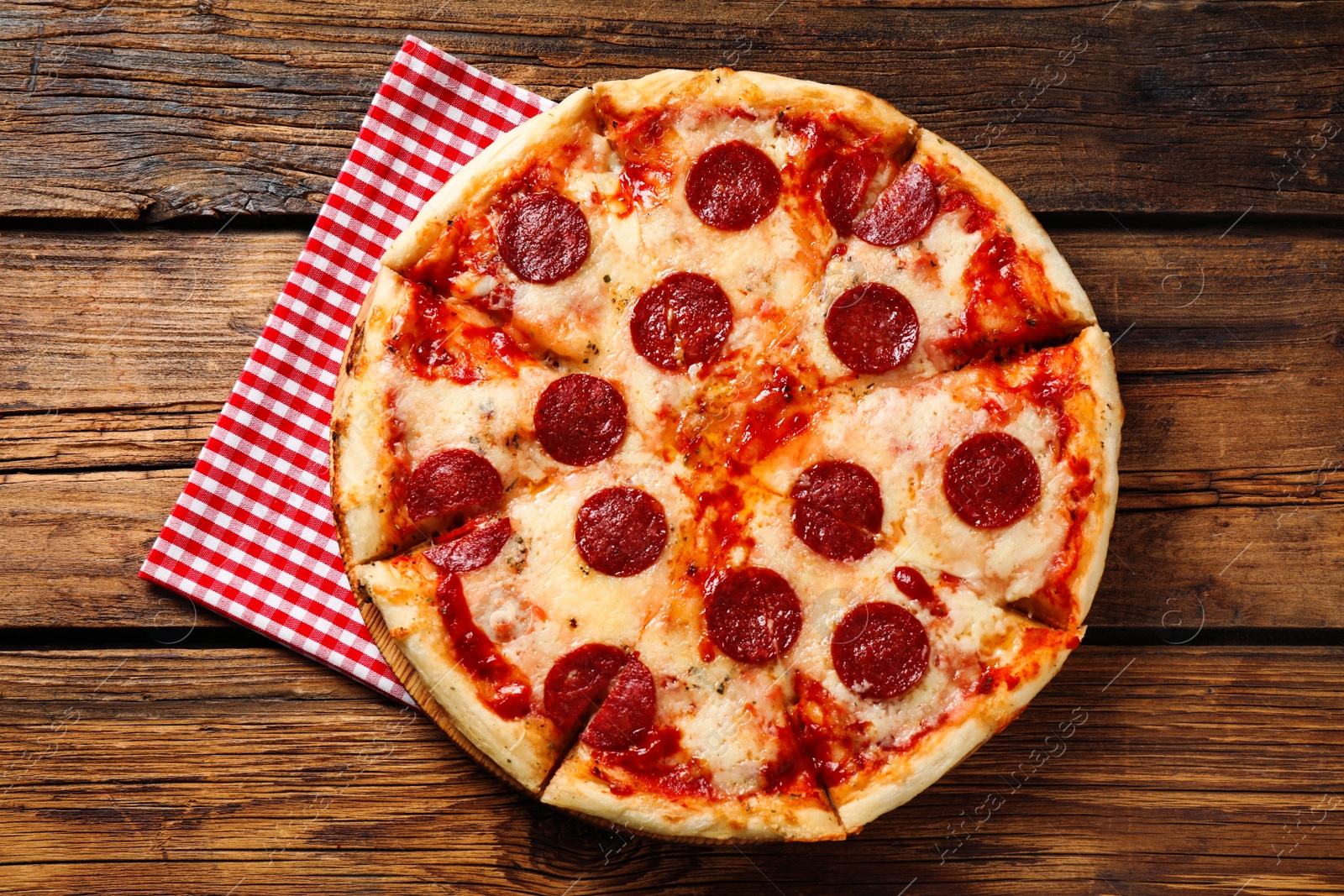 Photo of Hot delicious pepperoni pizza on wooden table, top view